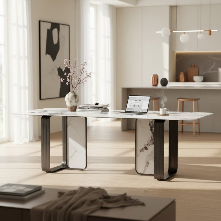 Modern marble dining table with a laptop, vase, and books in a bright, contemporary kitchen.