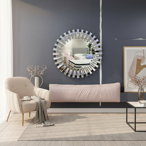 Modern living room with round sunburst wall mirror, beige armchair, and coffee table on rug