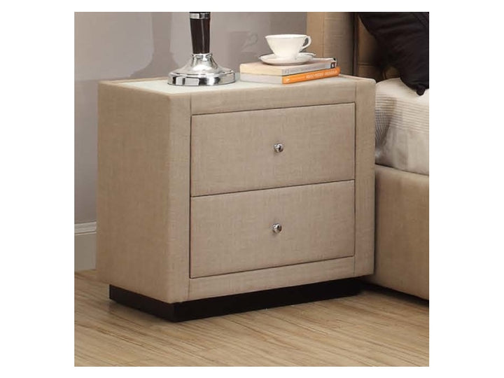 Modern beige upholstered bedside table with two drawers, lamp, and decor accessories